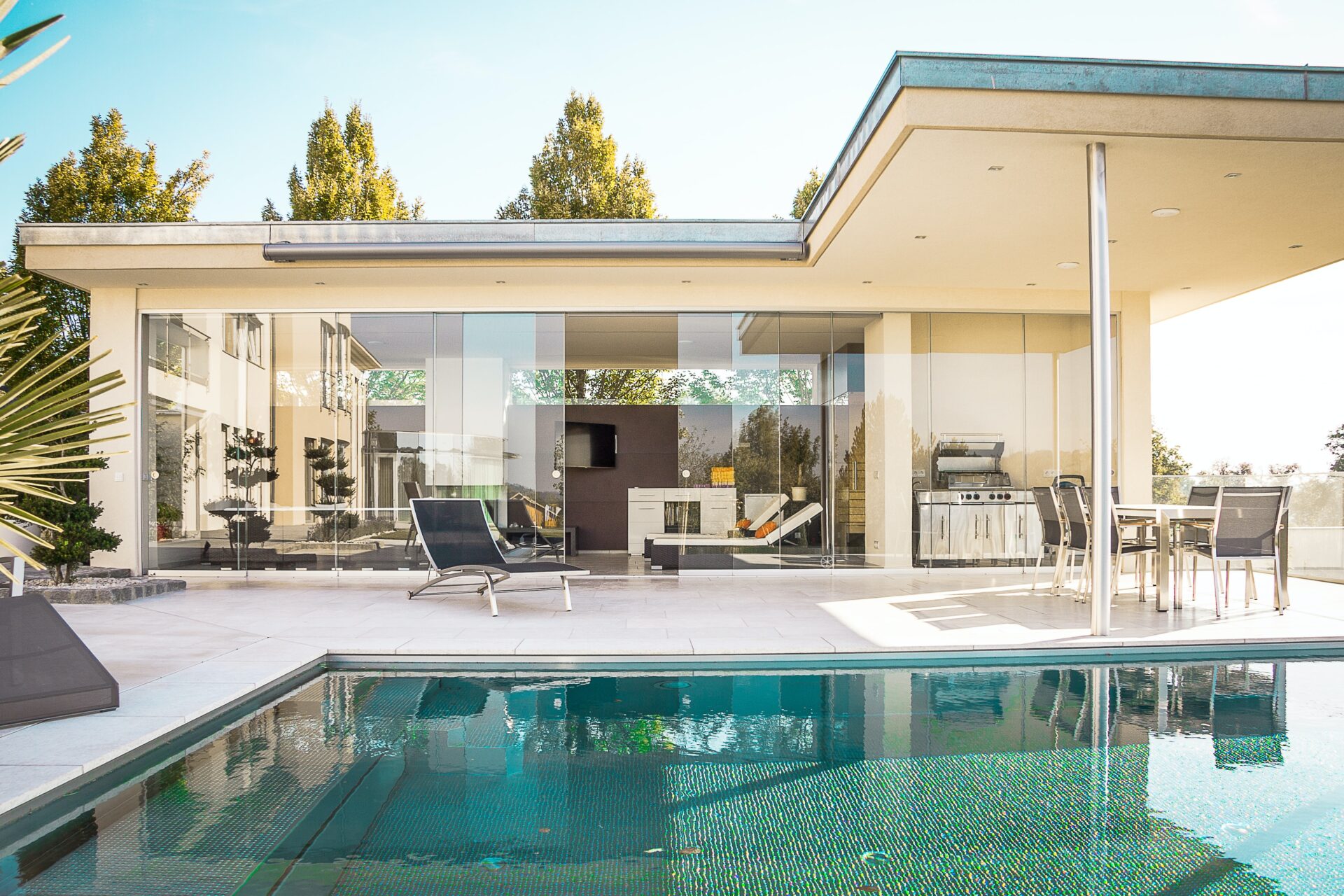 Rectangular pool with crystal clear water beside a glass patio home